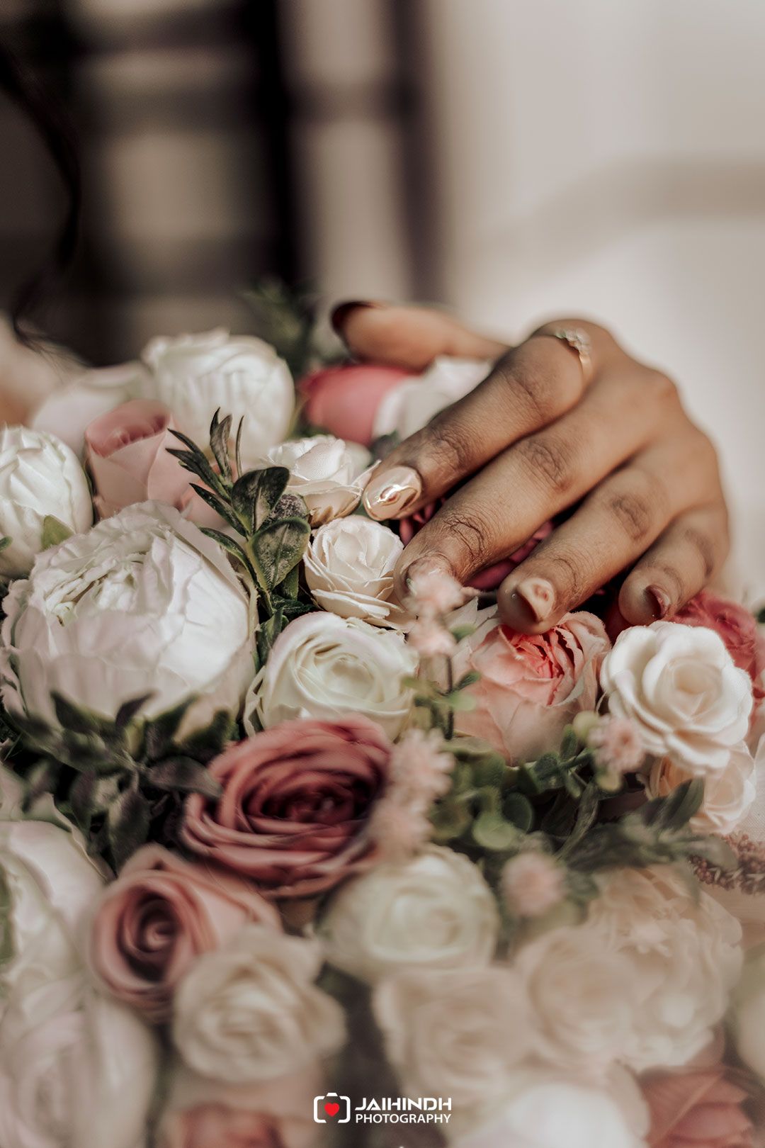 Close-up of a hand resting on a bouquet of white and pale pink roses.
