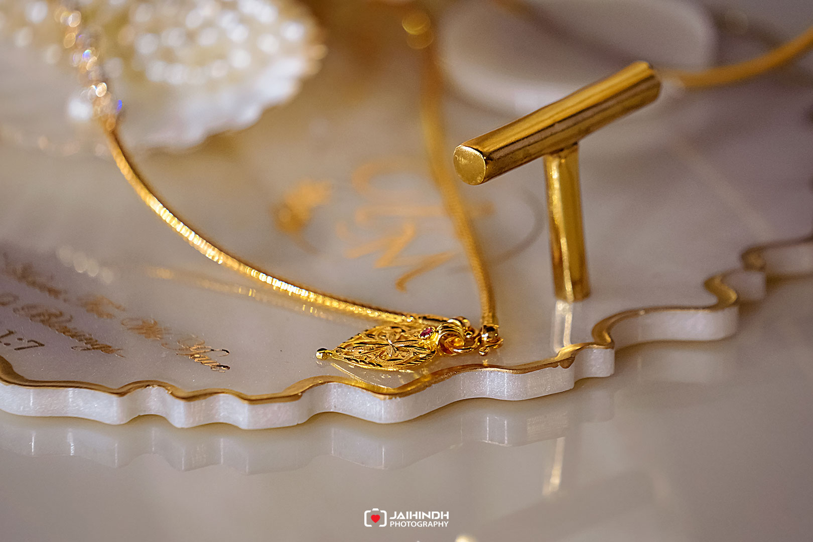 Close-up of a gold pendant and chain resting on a decorative white dish.