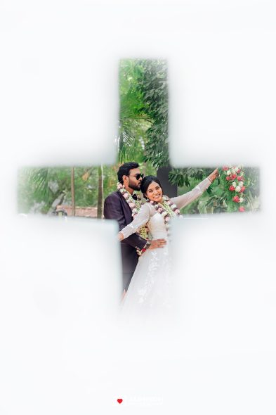 Bride and groom in wedding attire pose outdoors with garlands, framed by a large cross-shaped opening against a white background.