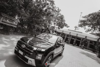Couple in a black SUV with hands raised from the sunroof, in front of CSI Cathedral Madurai.
