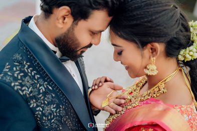 A bride in a pink sari and gold jewelry smiles as she and her groom hold hands in a tender, intimate moment of their wedding.”,