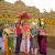 Indian wedding ceremony under a gold carved arch, couple adorned with garlands, surrounded by family.