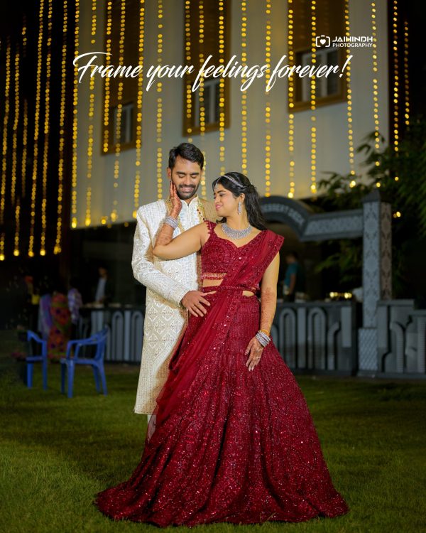 Couple in traditional Indian attire dancing outdoors at night, with warm string lights in the background.